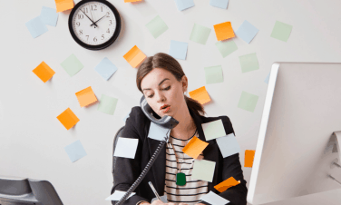 Female with lots of post it notes on her and the wall talking on the phone